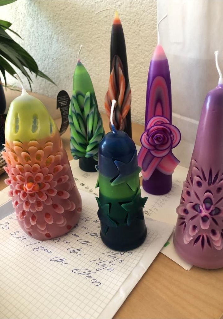 Verschiedene handverzierte Kerzen in Lila, Grün und Rosa